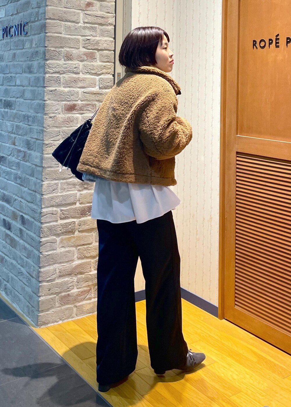 イエロー系のムートンコート、ブラック系のその他パンツ、グレー系のパンプスを着用したレディースの冬コーディネートの4枚目の写真