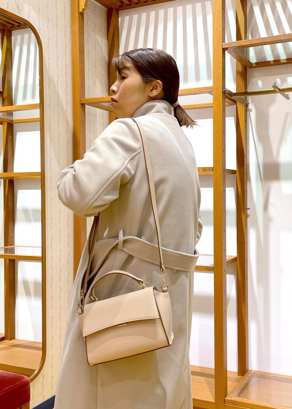 ブラック系のブーツ、ホワイト系のショルダーバッグ、レッド系のニット/セーターを着用したレディースの冬コーディネートの5枚目の写真