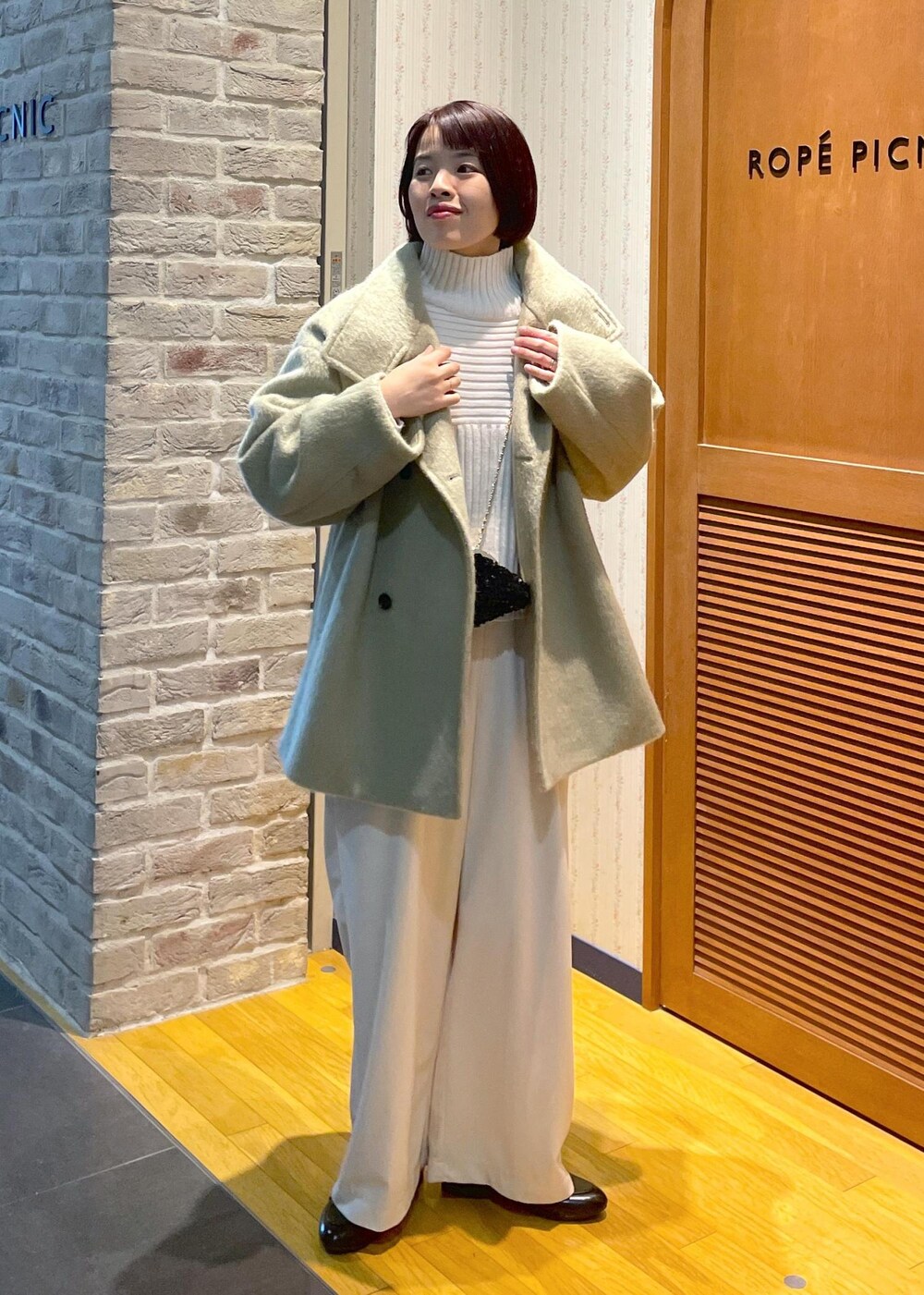 ホワイト系のニット/セーター、グリーン系のその他アウター、ブラック系のショルダーバッグを着用したレディースの冬コーディネートの5枚目の写真