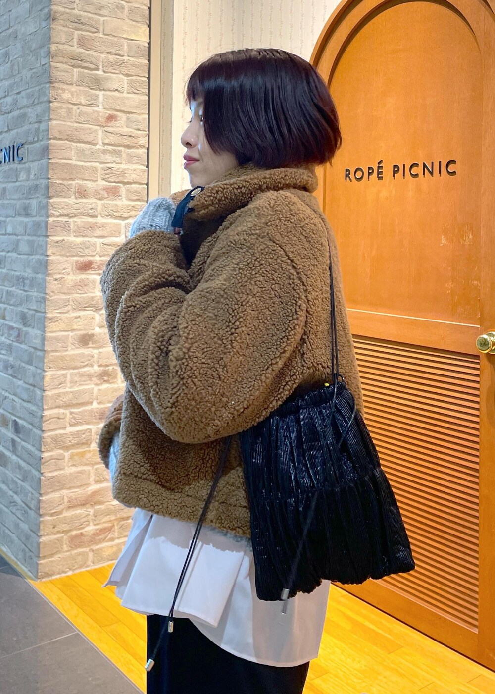 イエロー系のムートンコート、ブラック系のその他パンツ、グレー系のパンプスを着用したレディースの冬コーディネートの6枚目の写真