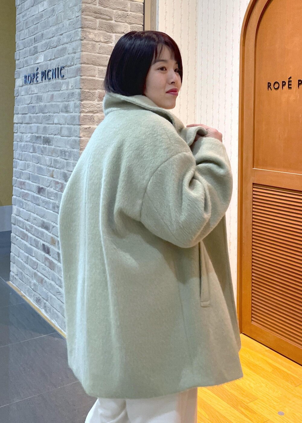 ホワイト系のニット/セーター、グリーン系のその他アウター、ブラック系のショルダーバッグを着用したレディースの冬コーディネートの8枚目の写真