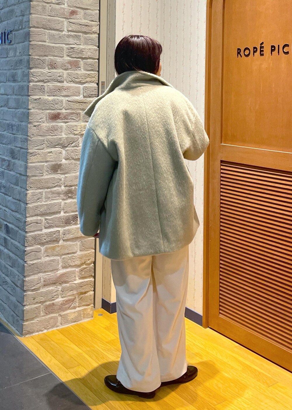 ホワイト系のニット/セーター、グリーン系のその他アウター、ブラック系のショルダーバッグを着用したレディースの冬コーディネートの3枚目の写真