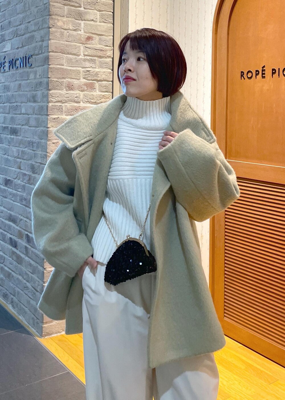 ホワイト系のニット/セーター、グリーン系のその他アウター、ブラック系のショルダーバッグを着用したレディースの冬コーディネートの6枚目の写真