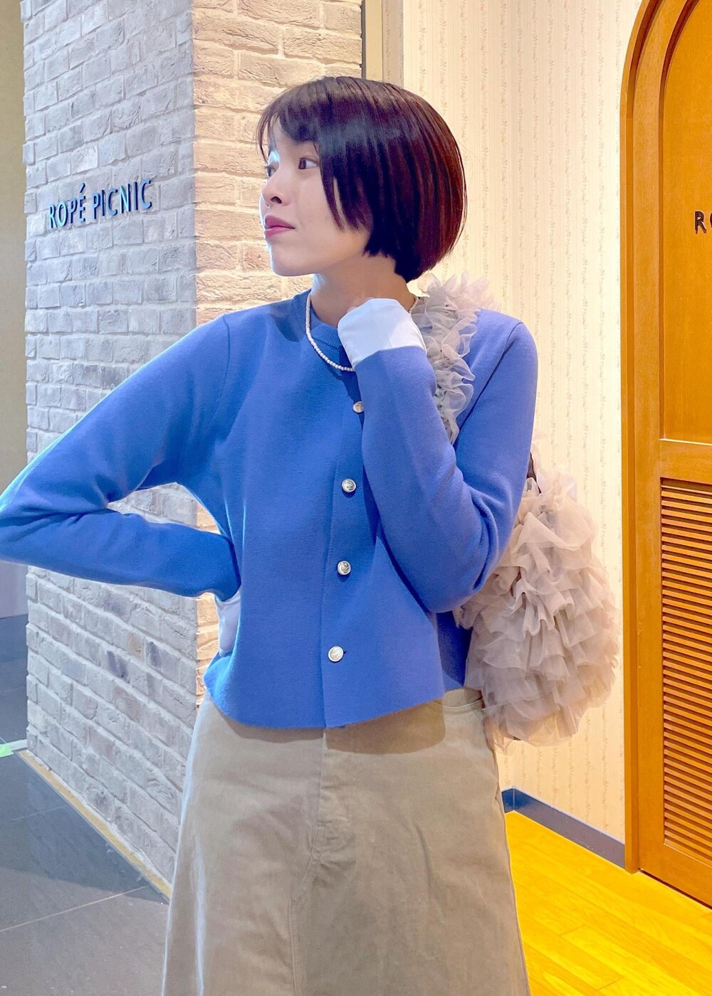 ブルー系のカーディガン/ボレロ、ベージュ系のスカート、ブルー系のTシャツ/カットソーを着用したレディースの冬コーディネートの6枚目の写真