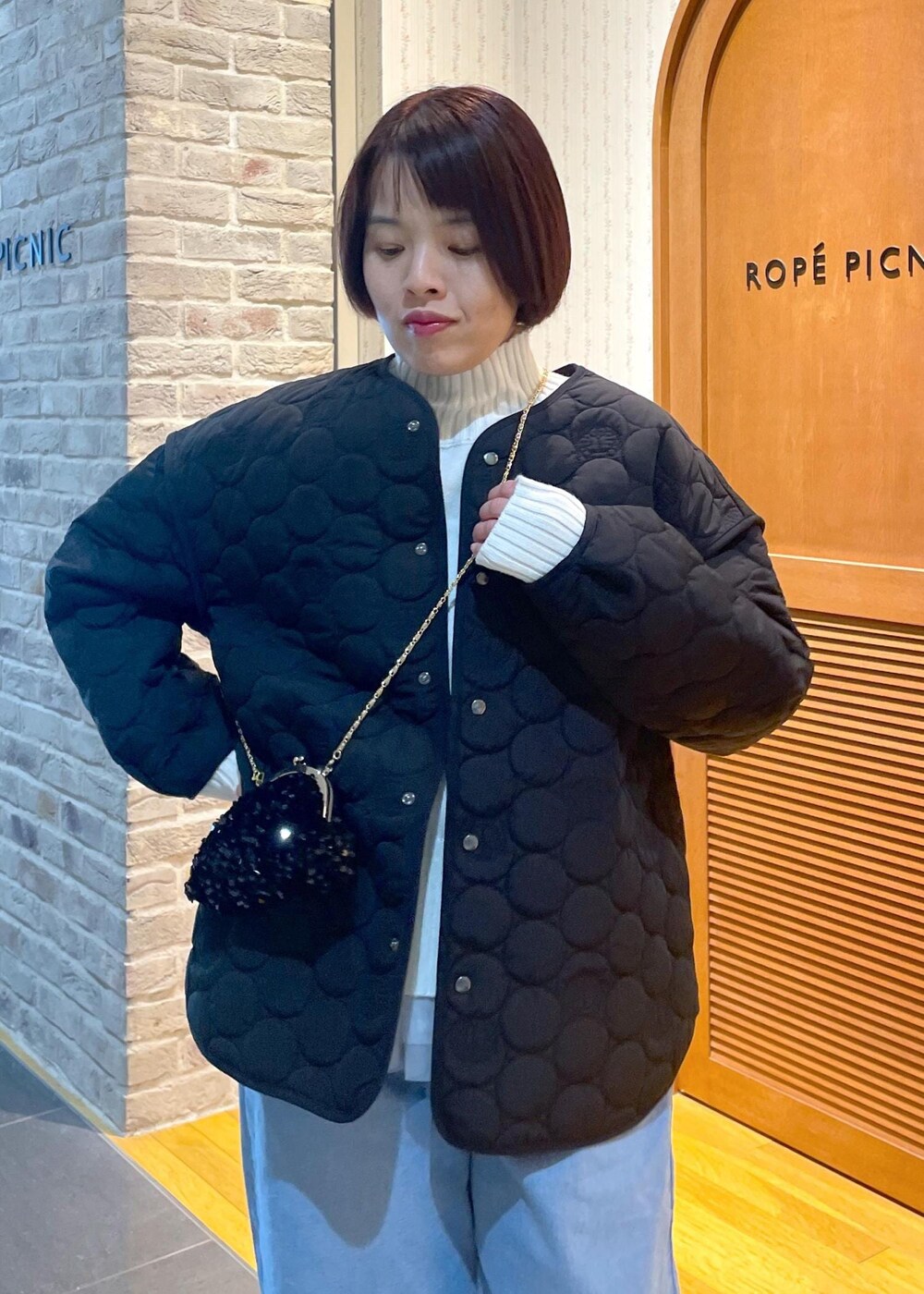 ホワイト系のニット/セーター、ブラック系のショルダーバッグ、グレー系のベストを着用したレディースの冬コーディネートの6枚目の写真