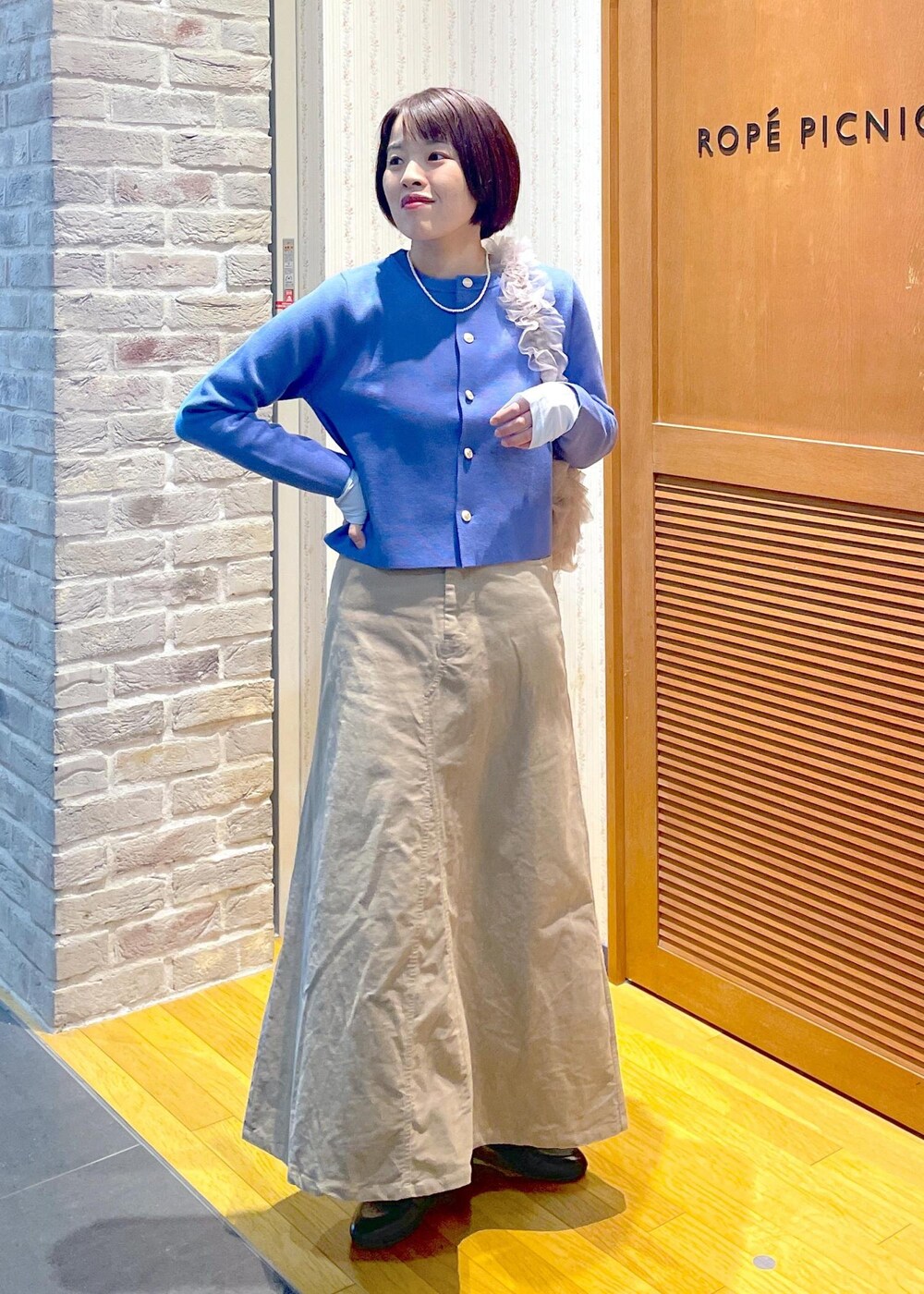 ブルー系のカーディガン/ボレロ、ベージュ系のスカート、ブルー系のTシャツ/カットソーを着用したレディースの冬コーディネートの5枚目の写真