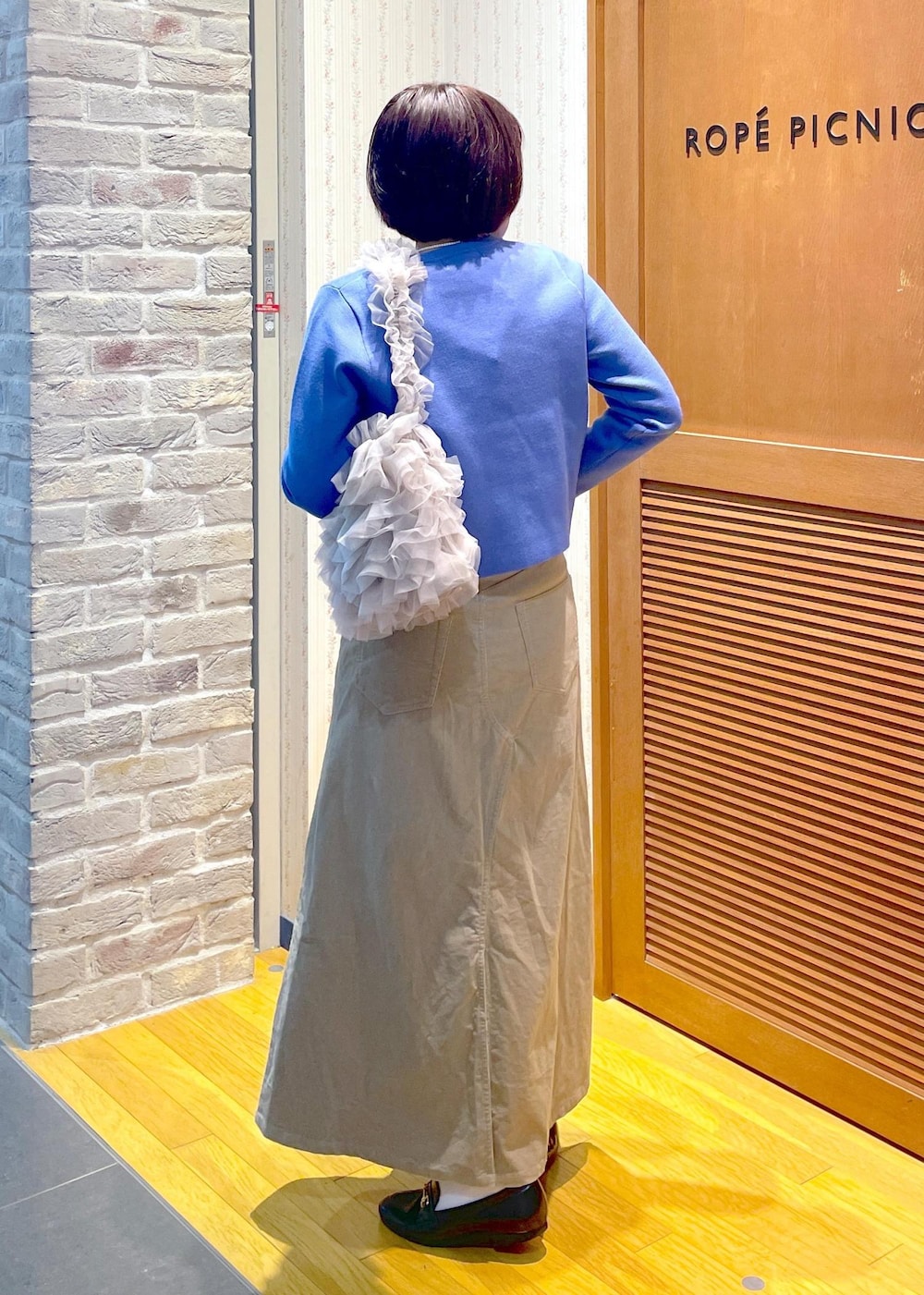 ブルー系のカーディガン/ボレロ、ベージュ系のスカート、ブルー系のTシャツ/カットソーを着用したレディースの冬コーディネートの3枚目の写真