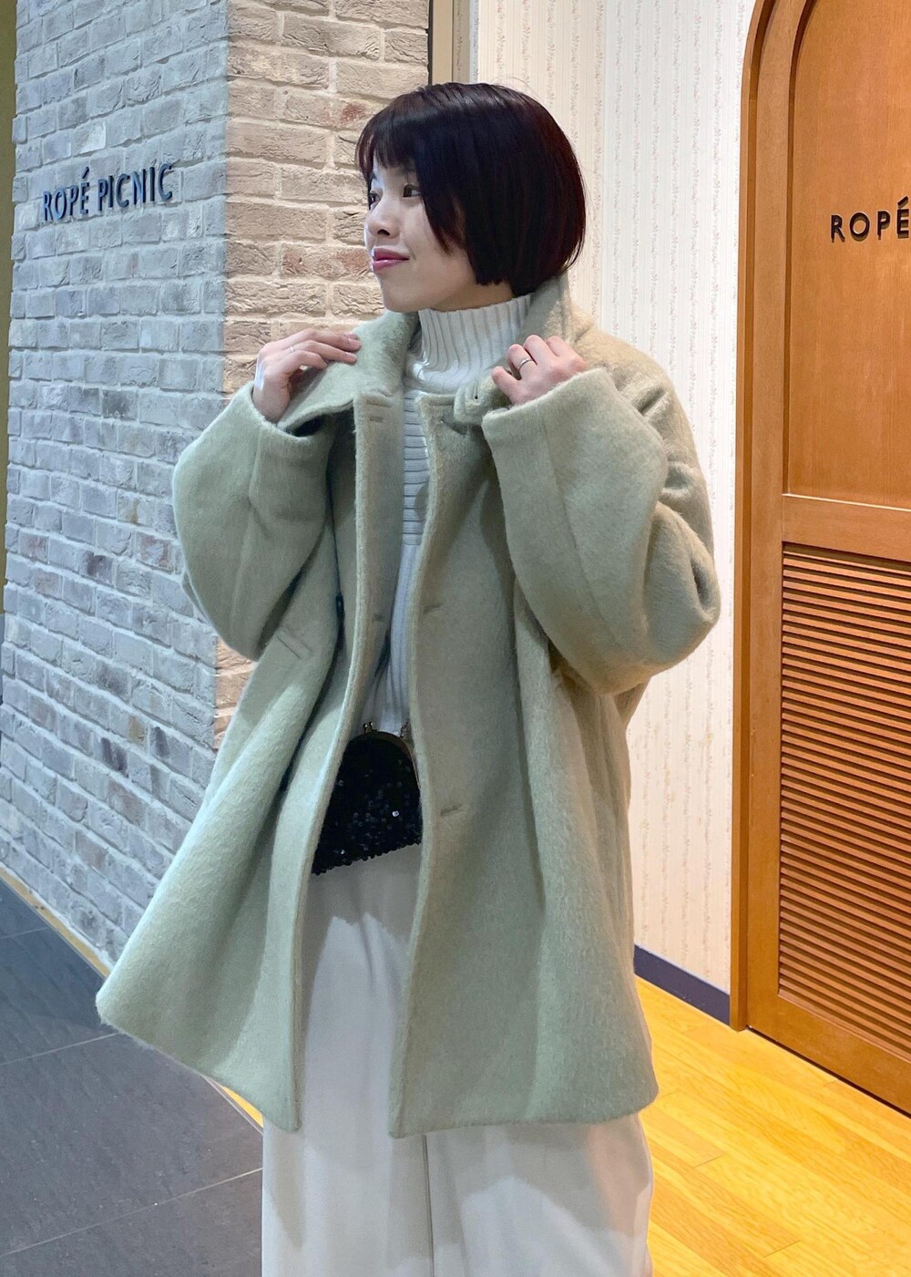 ホワイト系のニット/セーター、グリーン系のその他アウター、ブラック系のショルダーバッグを着用したレディースの冬コーディネートの9枚目の写真