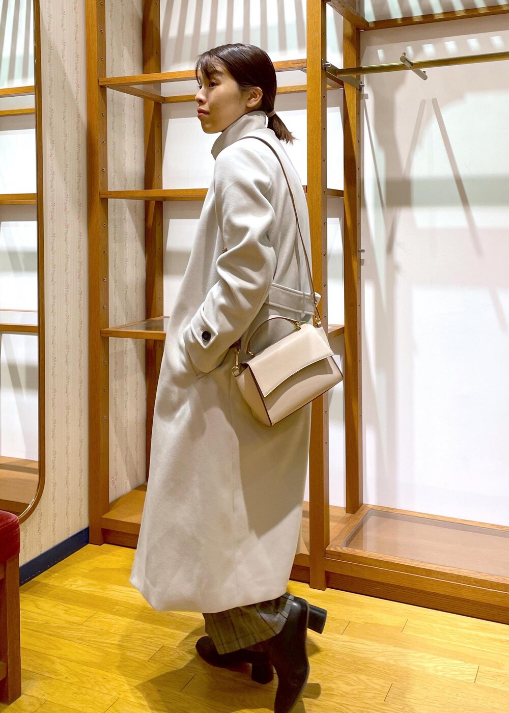 ブラック系のブーツ、ホワイト系のショルダーバッグ、レッド系のニット/セーターを着用したレディースの冬コーディネートの2枚目の写真