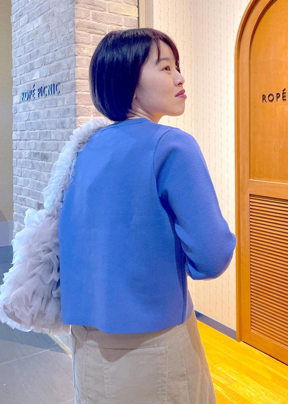 ブルー系のカーディガン/ボレロ、ベージュ系のスカート、ブルー系のTシャツ/カットソーを着用したレディースの冬コーディネートの8枚目の写真