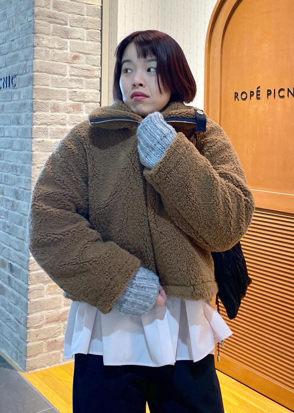 イエロー系のムートンコート、ブラック系のその他パンツ、グレー系のパンプスを着用したレディースの冬コーディネートの5枚目の写真