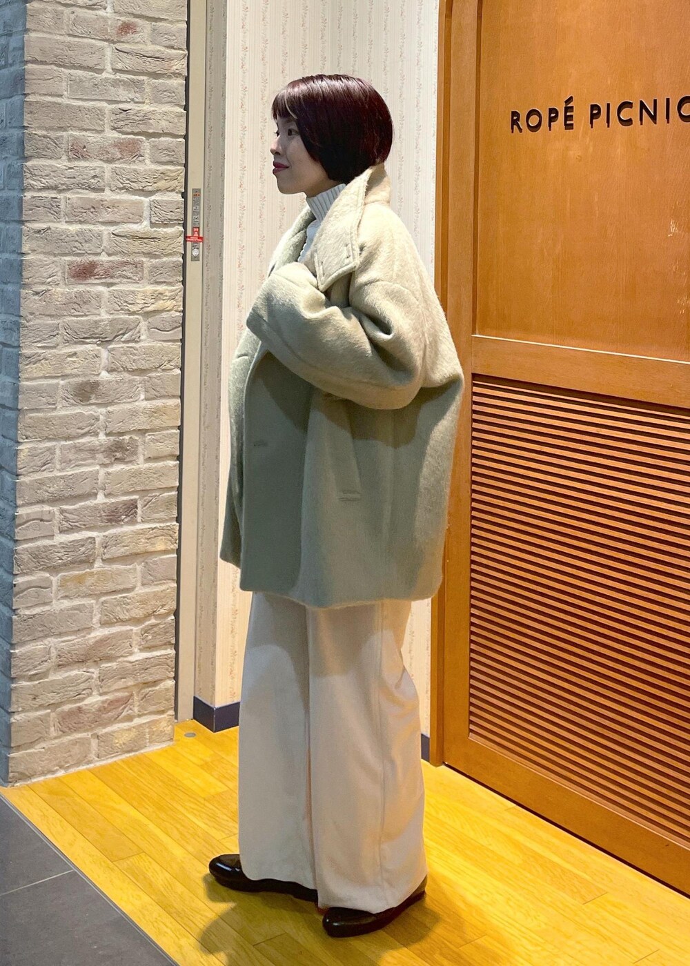 ホワイト系のニット/セーター、グリーン系のその他アウター、ブラック系のショルダーバッグを着用したレディースの冬コーディネートの2枚目の写真