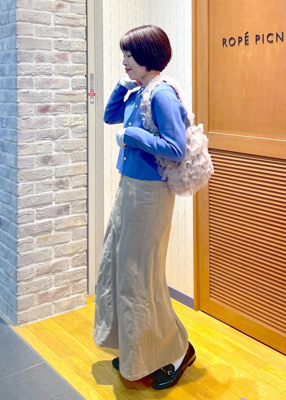 ブルー系のカーディガン/ボレロ、ベージュ系のスカート、ブルー系のTシャツ/カットソーを着用したレディースの冬コーディネートの2枚目の写真