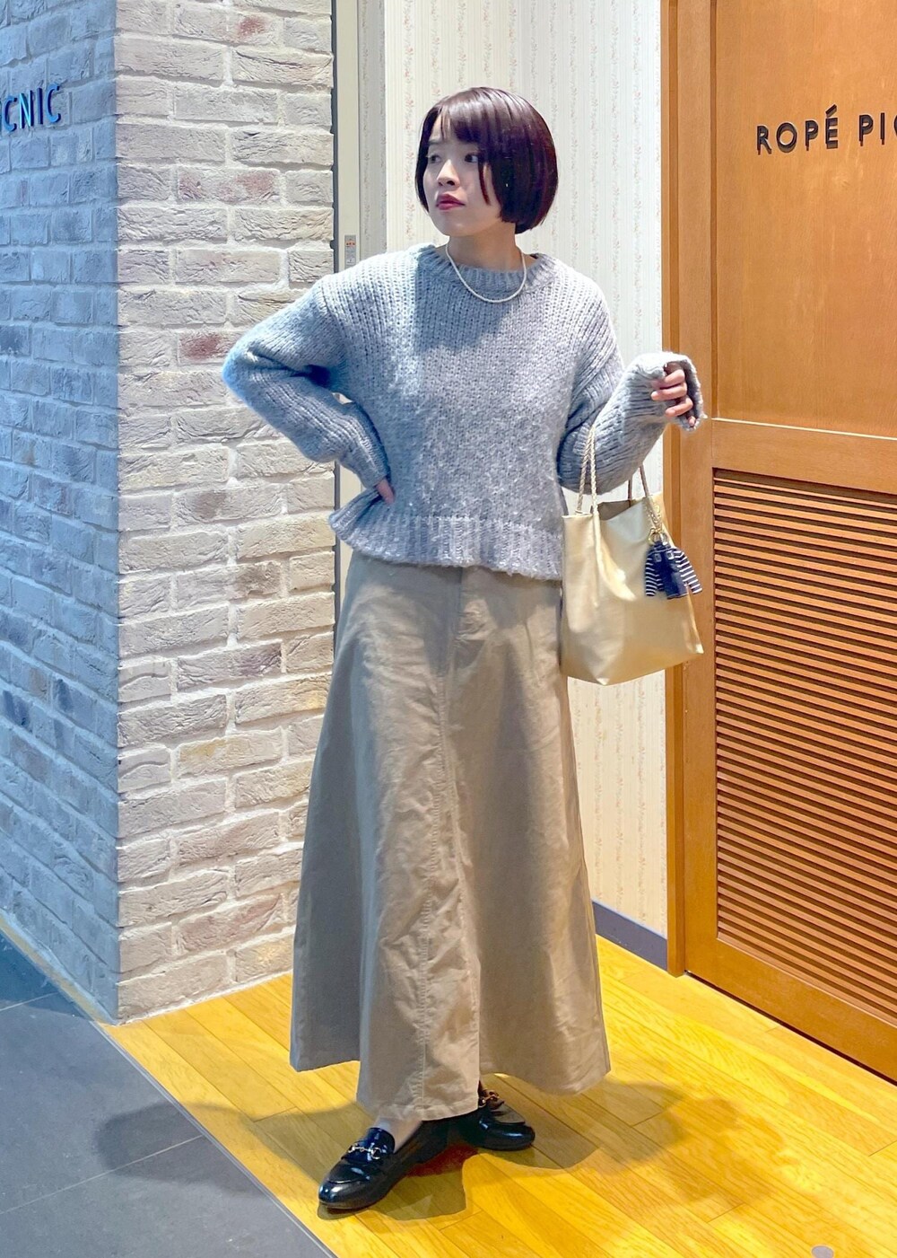 イエロー系のムートンコート、ベージュ系のスカート、ゴールド系のトートバッグを着用したレディースの冬コーディネートの9枚目の写真