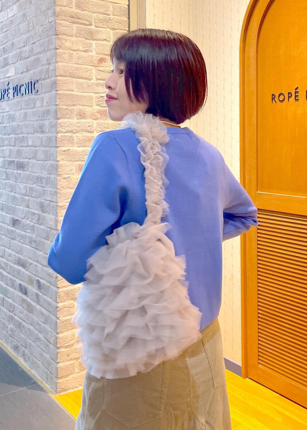 ブルー系のカーディガン/ボレロ、ベージュ系のスカート、ブルー系のTシャツ/カットソーを着用したレディースの冬コーディネートの9枚目の写真