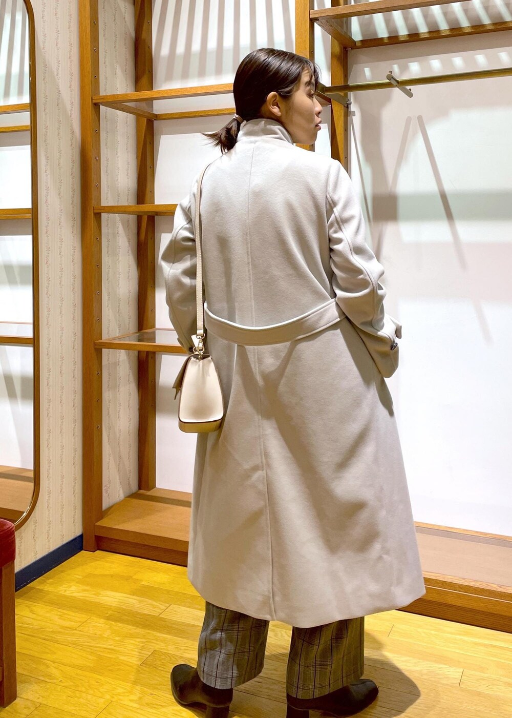 ブラック系のブーツ、ホワイト系のショルダーバッグ、レッド系のニット/セーターを着用したレディースの冬コーディネートの3枚目の写真