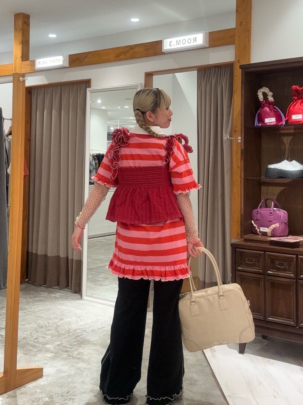 レッド系のキャミソール、ピンク系のチュニック、ブラック系のその他パンツを着用したレディースの秋コーディネートの3枚目の写真