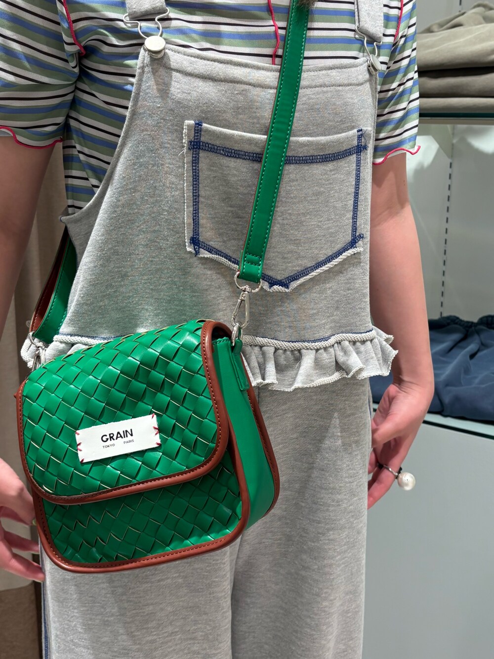 グリーン系のショルダーバッグ、グリーン系のTシャツ/カットソー、グレー系のサロペット/オーバーオールを着用したレディースの夏コーディネートの4枚目の写真