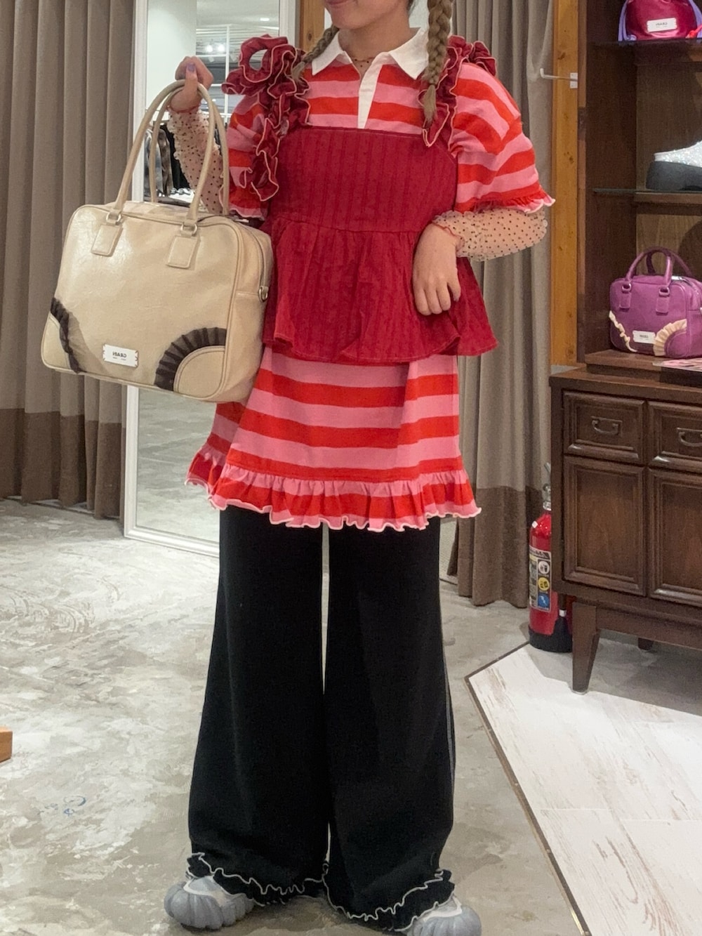 レッド系のキャミソール、ピンク系のチュニック、ブラック系のその他パンツを着用したレディースの秋コーディネートの2枚目の写真