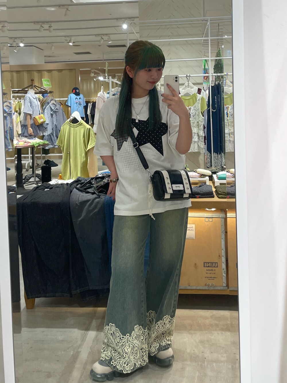 ブルー系のデニムパンツ、ブラック系のトートバッグ、ホワイト系のTシャツ/カットソーを着用したレディースの夏コーディネートの2枚目の写真