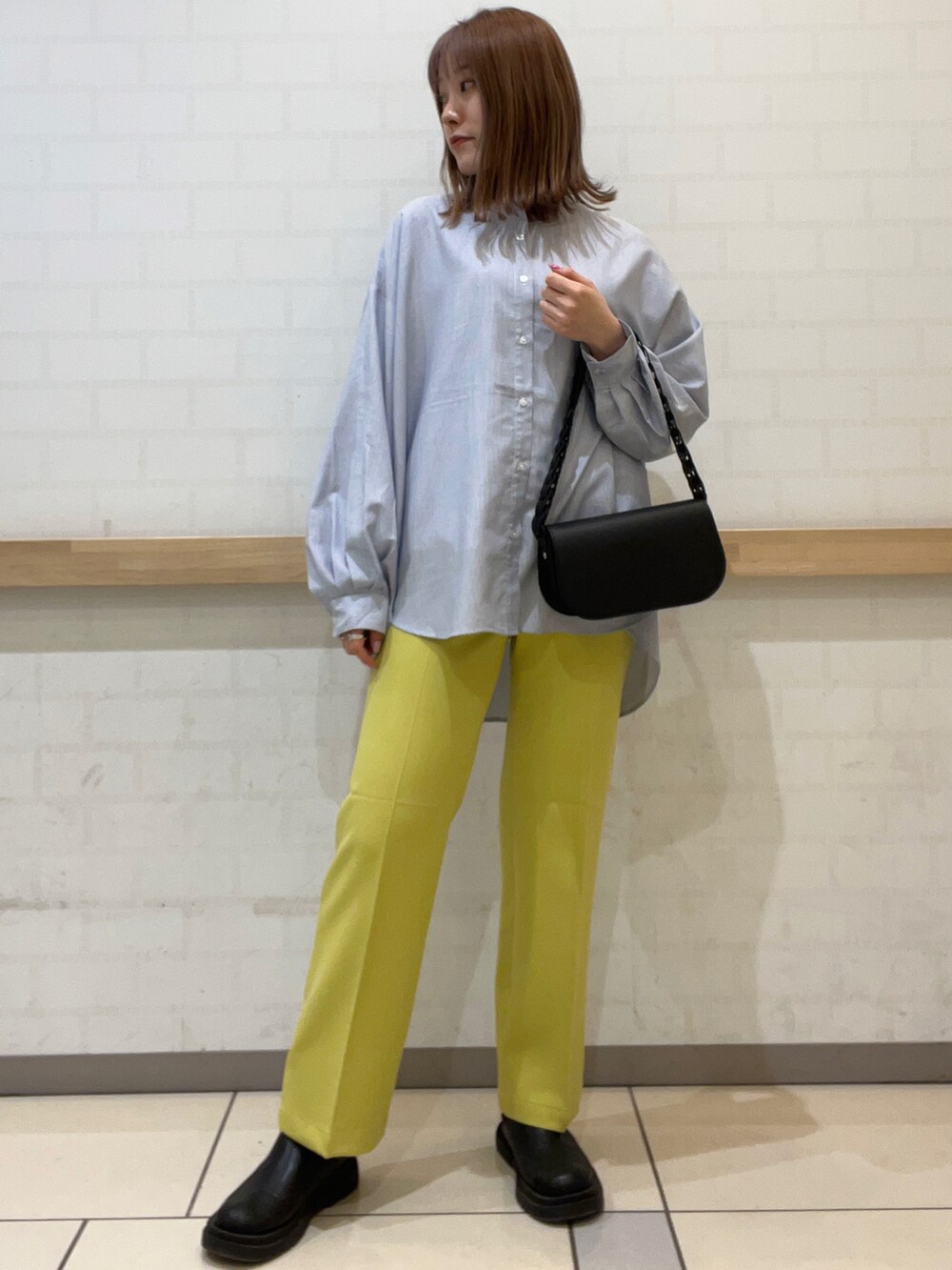 イエロー系のその他パンツ、ブルー系のシャツ/ブラウス、ブラック系のハンドバッグを着用したレディースの冬コーディネートの2枚目の写真