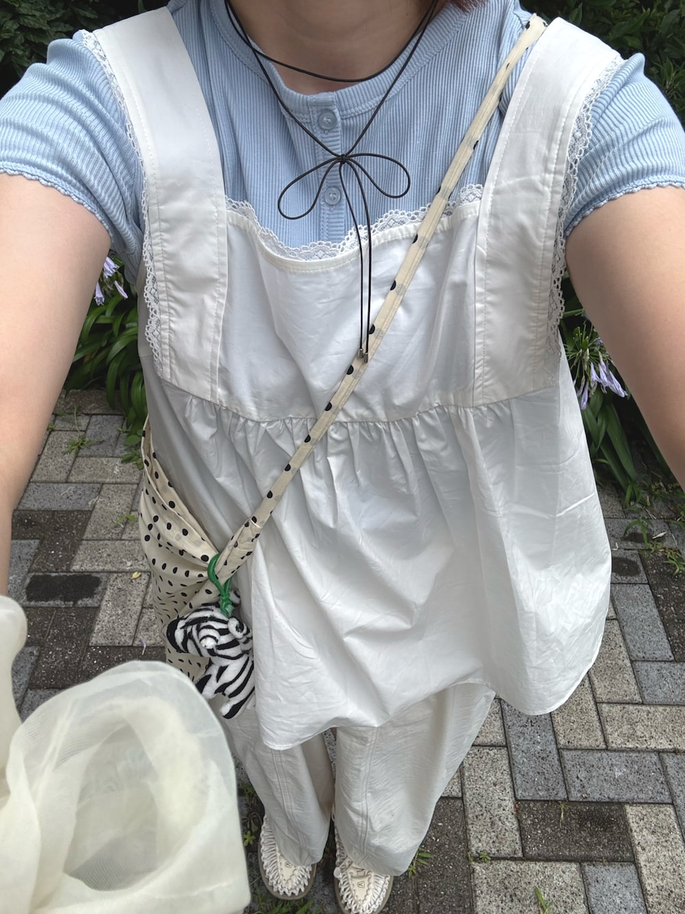 ホワイト系のチノパンツ、ホワイト系のスニーカー、ベージュ系のショルダーバッグを着用したレディースの夏コーディネートの2枚目の写真