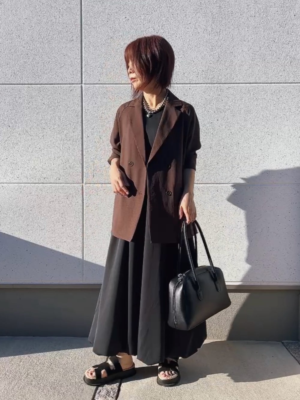 ブラウン系のジャケット/アウター、ブラック系のワンピース/ドレス、ブラック系のバッグを着用したレディースの秋コーディネートの2枚目の写真
