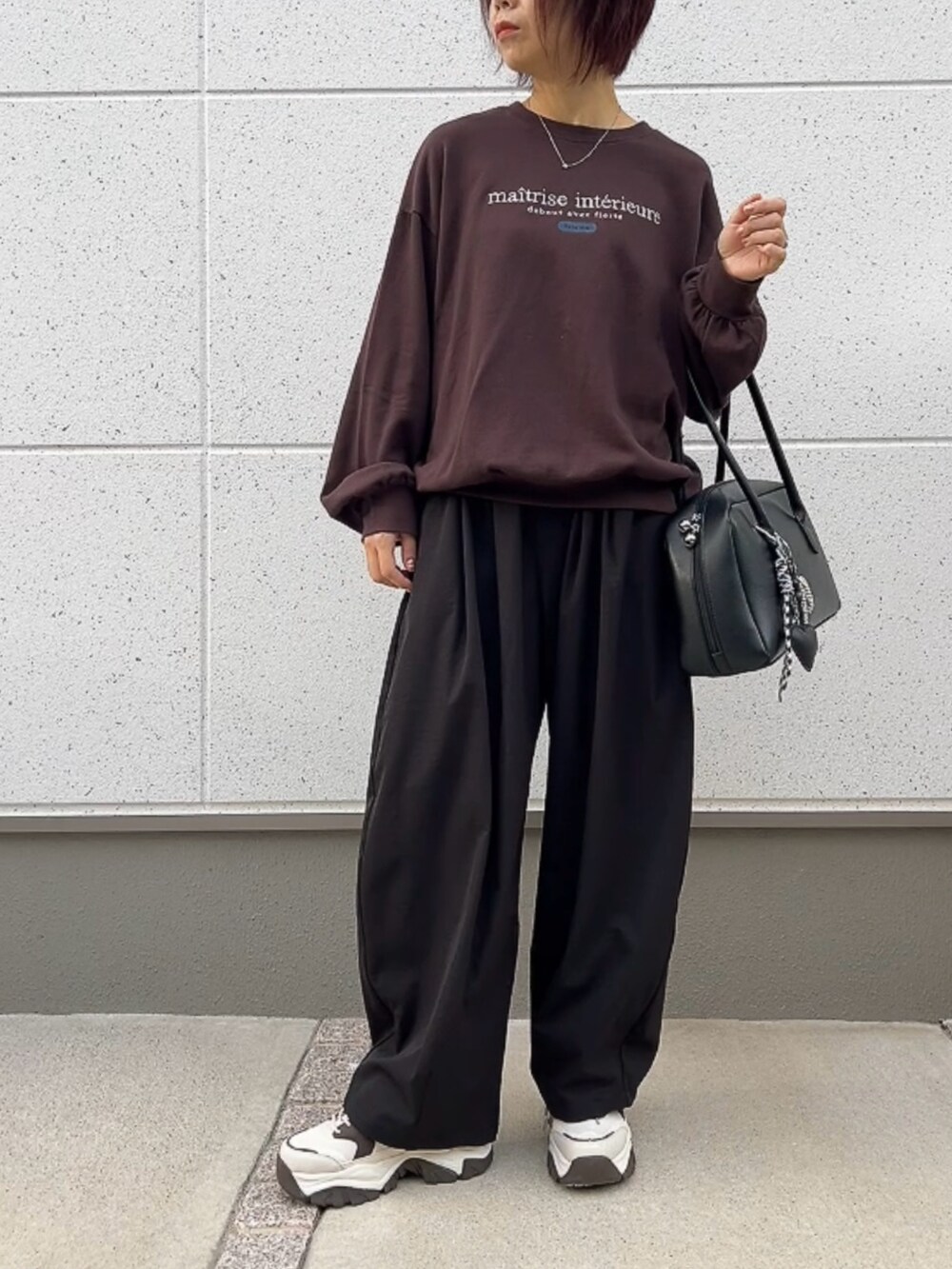 ブラウン系のスウェット、ブラック系のパンツ、ブラック系のバッグを着用したレディースの秋コーディネートの3枚目の写真