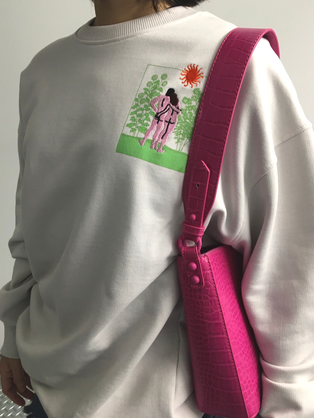 ホワイト系のスウェット、ピンク系のハンドバッグを着用したレディースの夏コーディネートの2枚目の写真