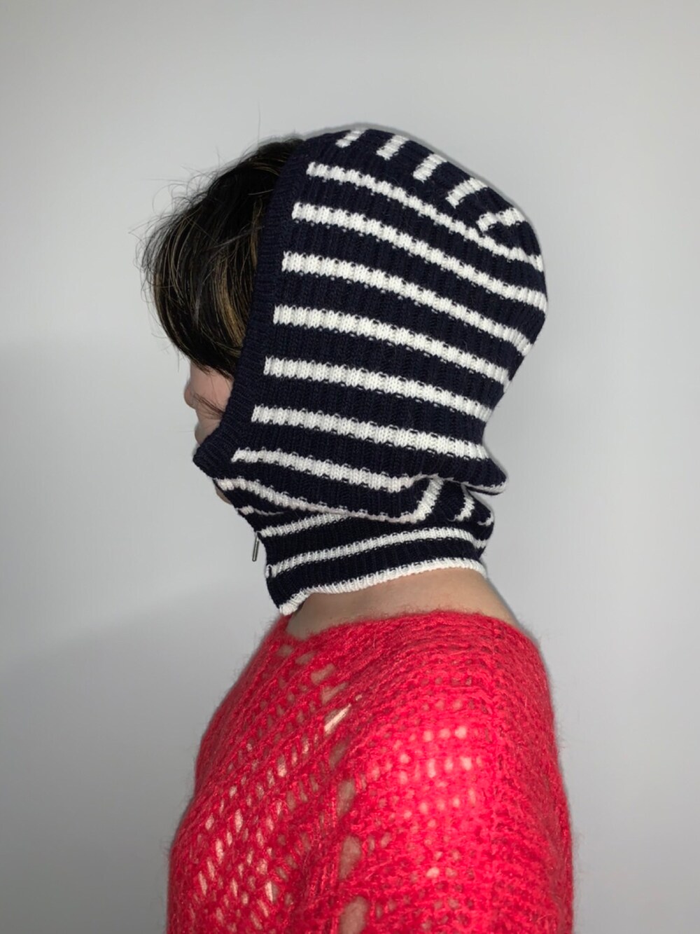 レッド系のニット/セーター、ブルー系のニットキャップ/ビーニーを着用したレディースの秋コーディネートの4枚目の写真