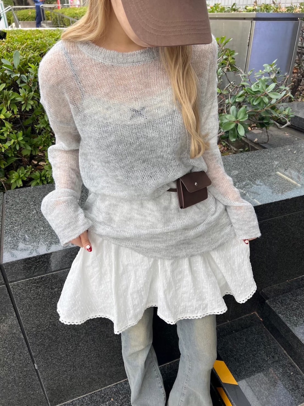 グレー系のニット/セーター、ホワイト系のスカート、ブルー系のデニムパンツを着用したレディースの冬コーディネートの4枚目の写真