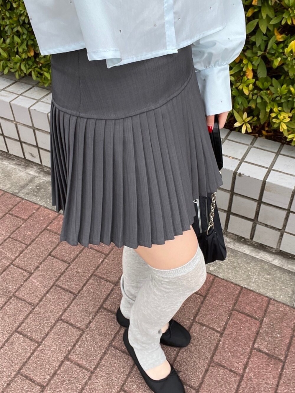 グレー系のスカート、ブラック系のショルダーバッグ、ブルー系のシャツ/ブラウスを着用したレディースの春コーディネートの5枚目の写真