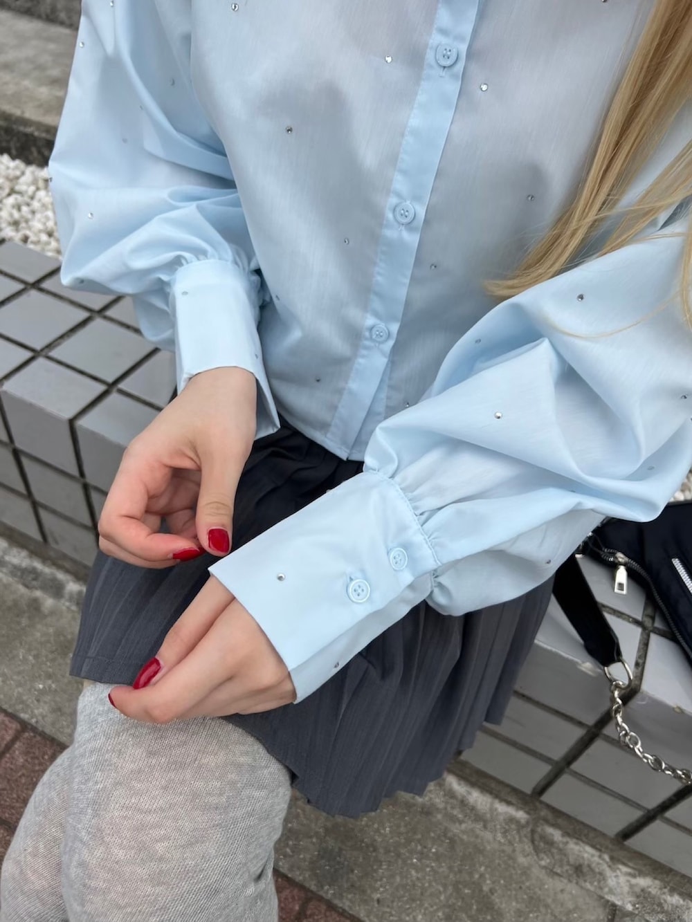 グレー系のスカート、ブラック系のショルダーバッグ、ブルー系のシャツ/ブラウスを着用したレディースの春コーディネートの2枚目の写真