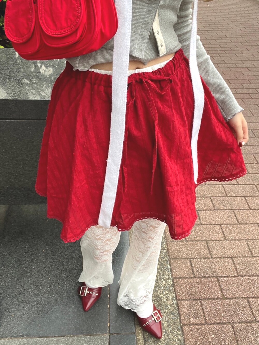 ホワイト系のその他パンツ、レッド系のスカート、グレー系のTシャツ/カットソーを着用したレディースの冬コーディネートの4枚目の写真