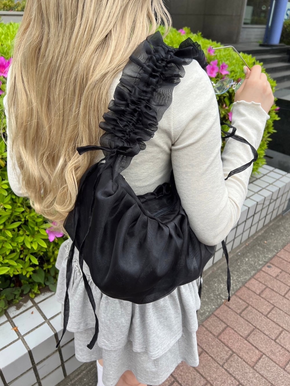 ホワイト系のTシャツ/カットソー、グレー系のスカート、ブラック系のショルダーバッグを着用したレディースの春コーディネートの2枚目の写真