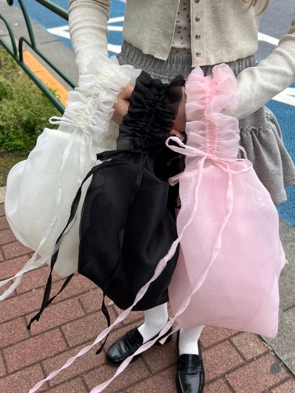 ホワイト系のTシャツ/カットソー、グレー系のスカート、ブラック系のショルダーバッグを着用したレディースの春コーディネートの6枚目の写真