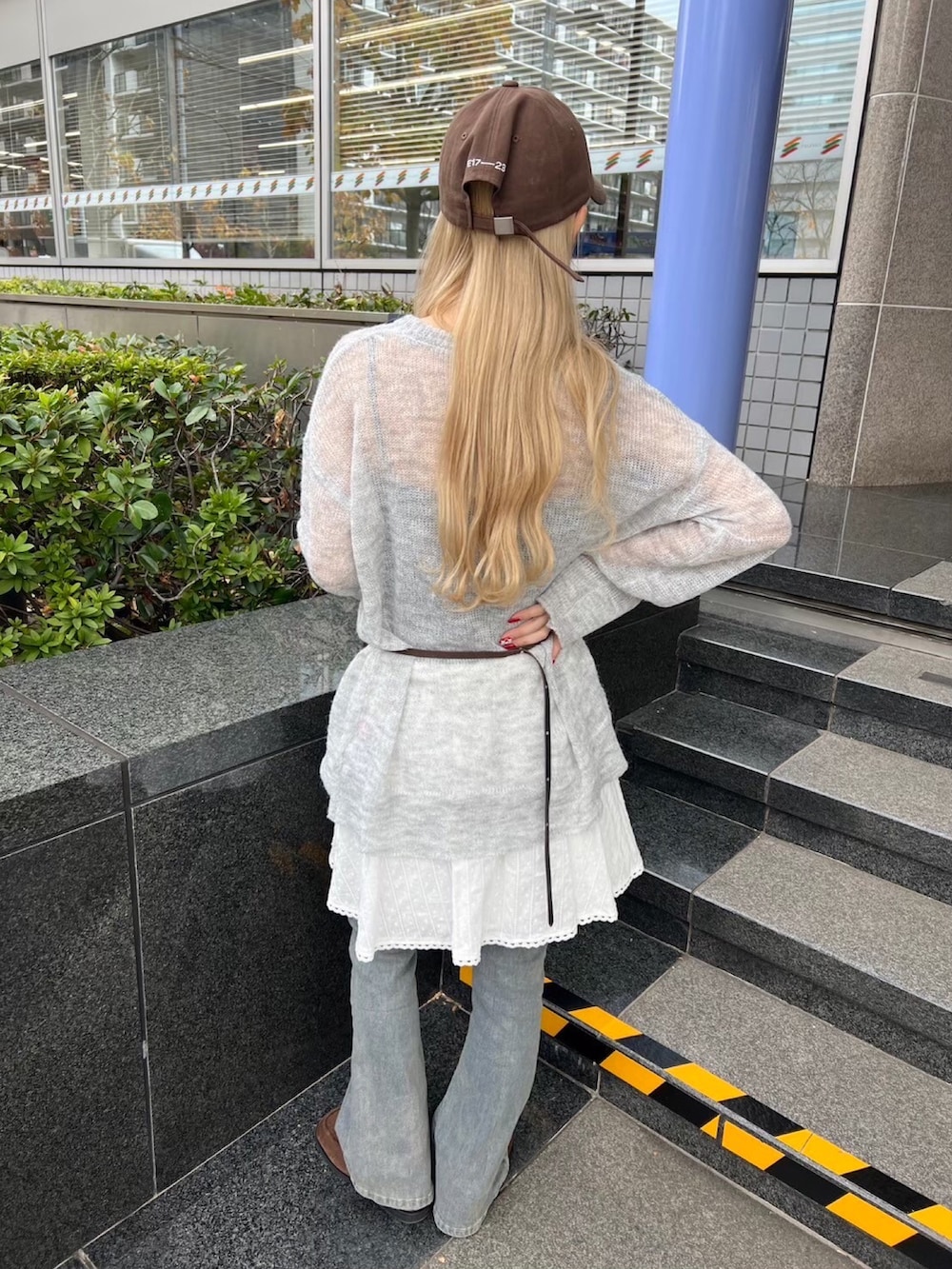 グレー系のニット/セーター、ホワイト系のスカート、ブルー系のデニムパンツを着用したレディースの冬コーディネートの2枚目の写真