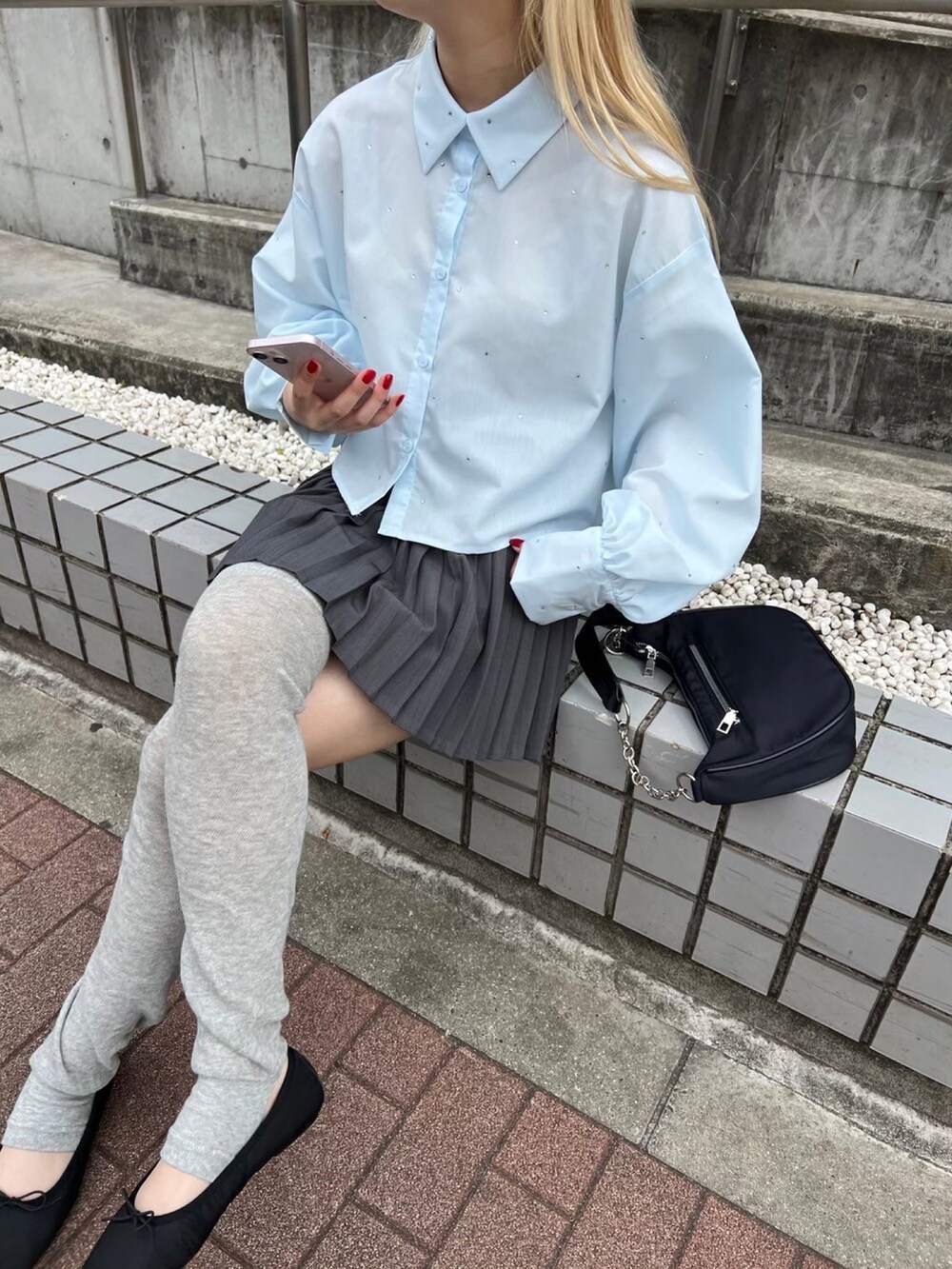 グレー系のスカート、ブラック系のショルダーバッグ、ブルー系のシャツ/ブラウスを着用したレディースの春コーディネートの3枚目の写真