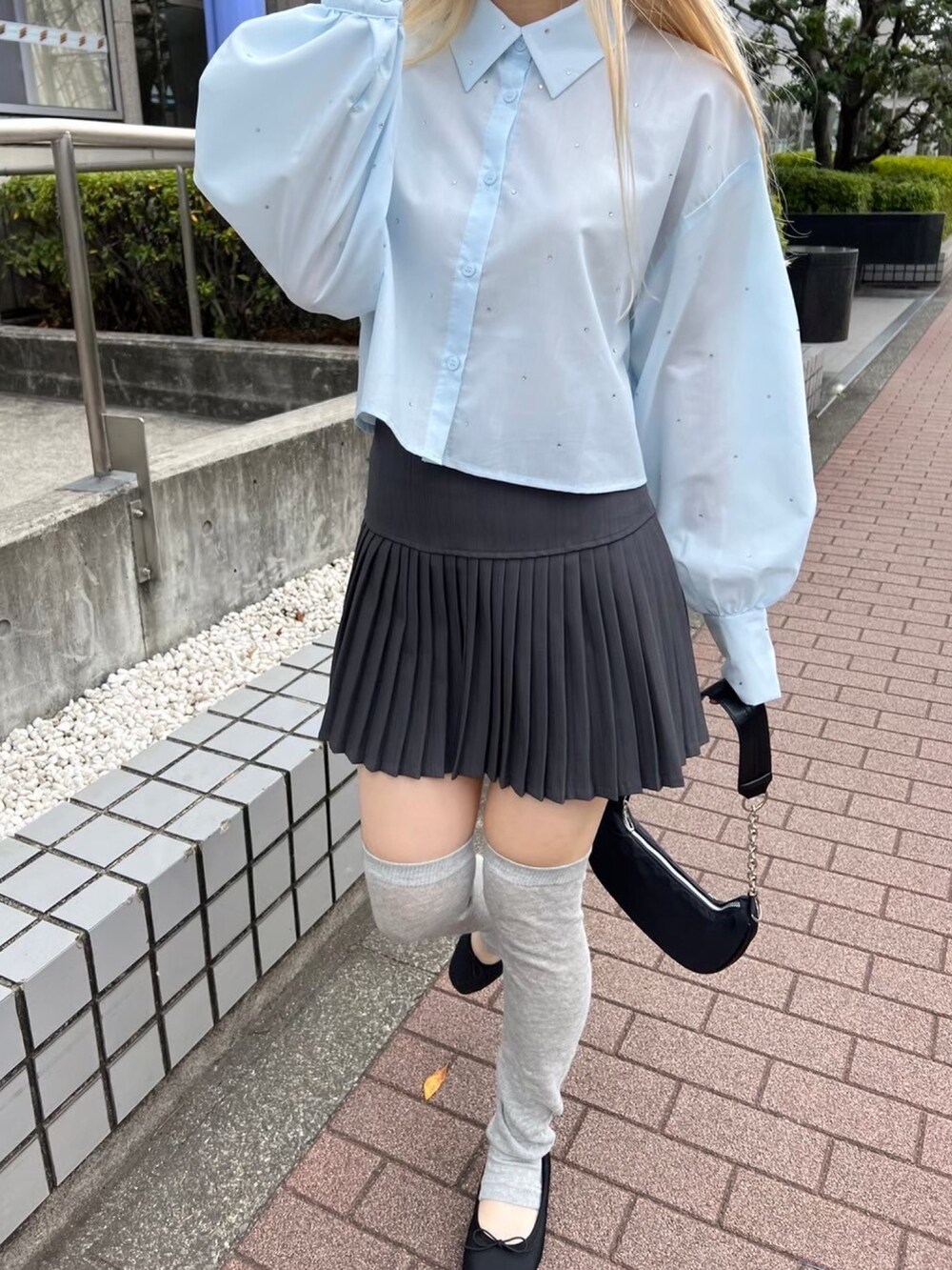 グレー系のスカート、ブラック系のショルダーバッグ、ブルー系のシャツ/ブラウスを着用したレディースの春コーディネートの4枚目の写真