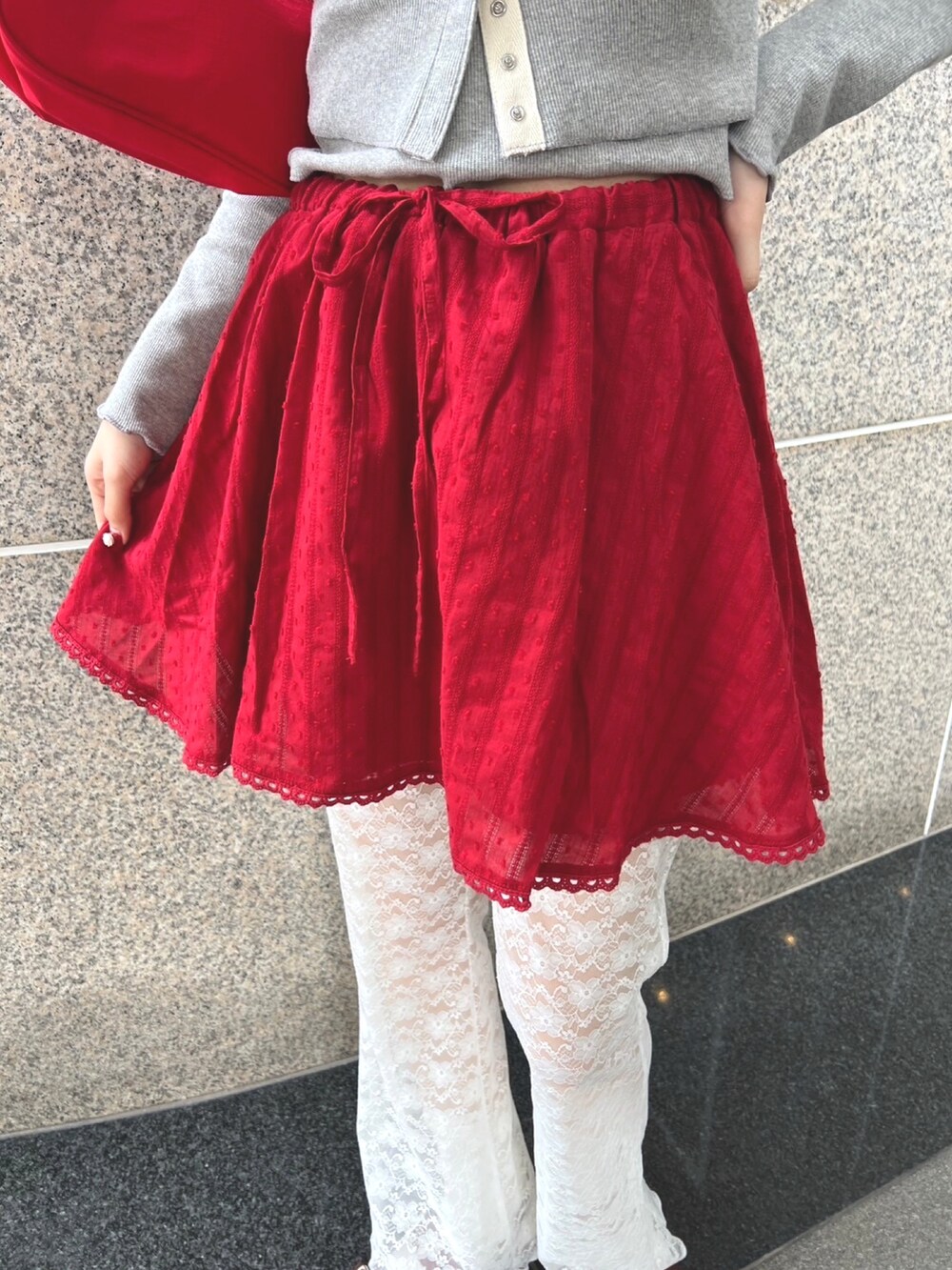 ホワイト系のその他パンツ、レッド系のスカート、グレー系のTシャツ/カットソーを着用したレディースの冬コーディネートの5枚目の写真