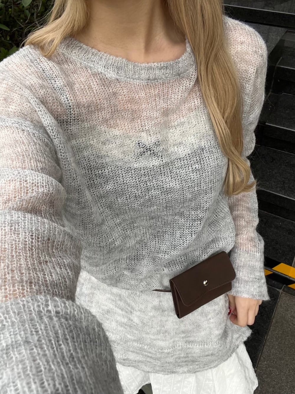 グレー系のニット/セーター、ホワイト系のスカート、ブルー系のデニムパンツを着用したレディースの冬コーディネートの3枚目の写真