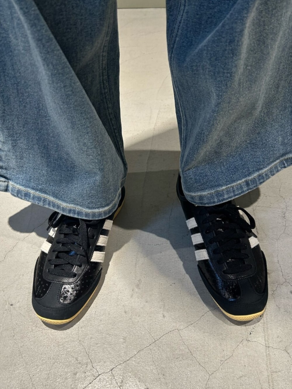 グレー系のジャージ、ブルー系のデニムパンツ、ブラック系のスニーカーを着用したメンズの冬コーディネートの2枚目の写真