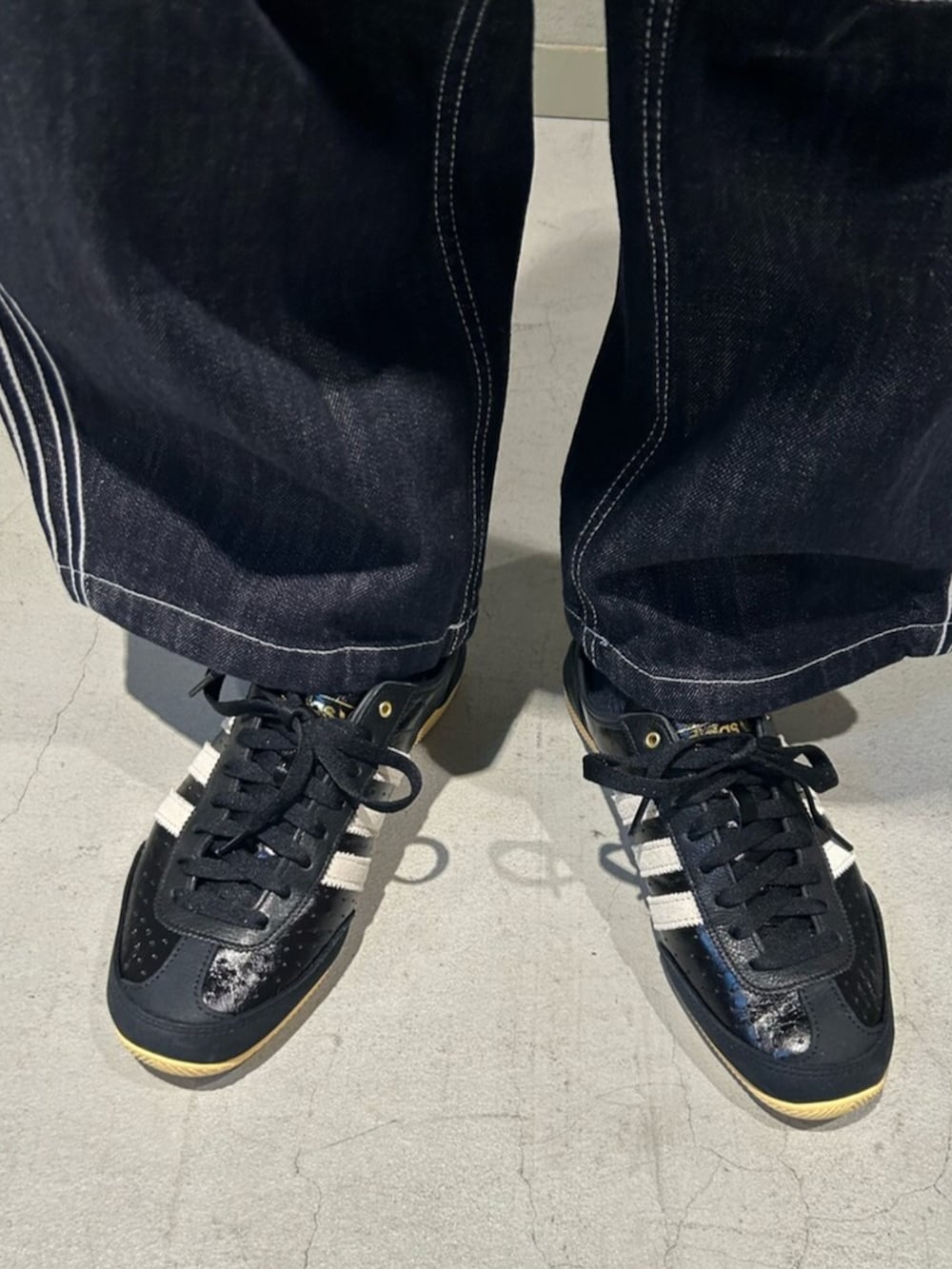 ブラック系のスニーカー、ホワイト系のスウェット、ブルー系のデニムパンツを着用したメンズの冬コーディネートの4枚目の写真