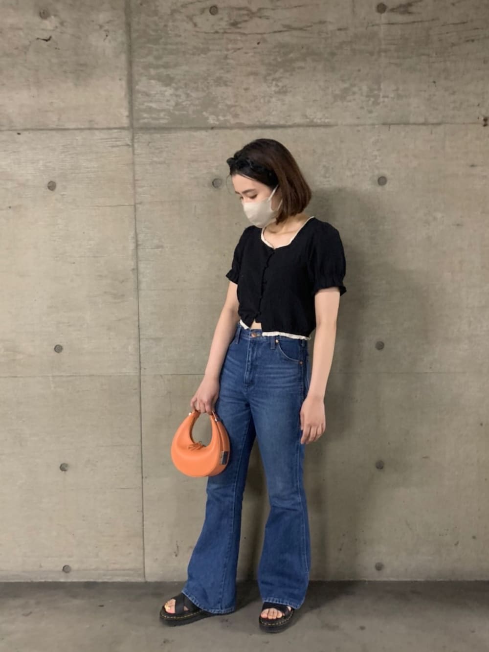 ブルー系のデニムパンツ、ブラック系のサンダル、オレンジ系のハンドバッグを着用したレディースの夏コーディネートの3枚目の写真