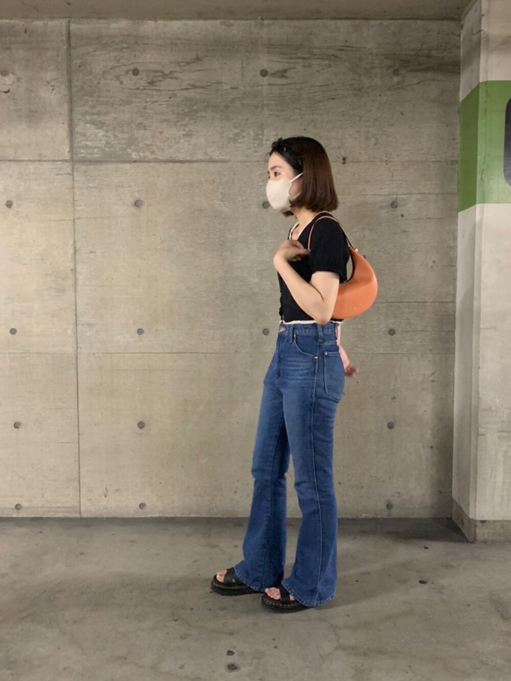 ブルー系のデニムパンツ、ブラック系のサンダル、オレンジ系のハンドバッグを着用したレディースの夏コーディネートの2枚目の写真