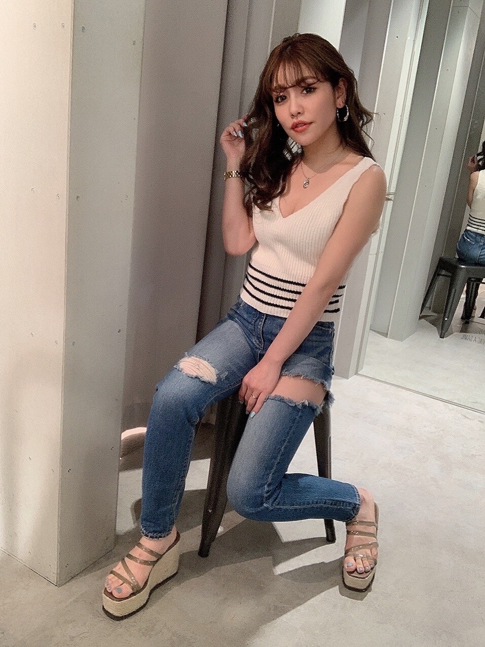 ブルー系のデニムパンツ、ベージュ系のサンダル、ホワイト系のニット/セーターを着用したレディースの春コーディネートの2枚目の写真