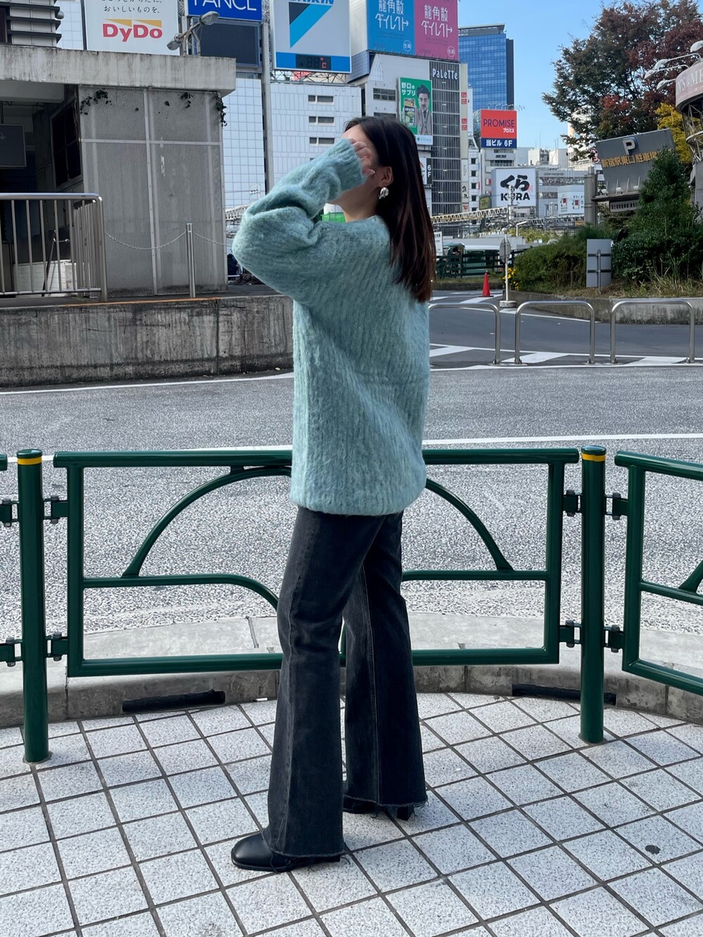 ブルー系のニット/セーター、ブラック系のデニムパンツ、ブラック系のブーツを着用したレディースの秋コーディネートの2枚目の写真