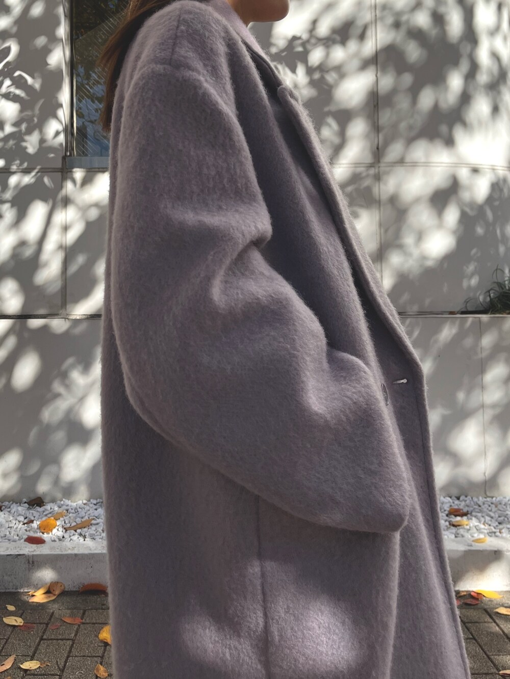 パープル系のチェスターコート、ブラック系のワンピース、ブラック系のブーツを着用したレディースの冬コーディネートの5枚目の写真