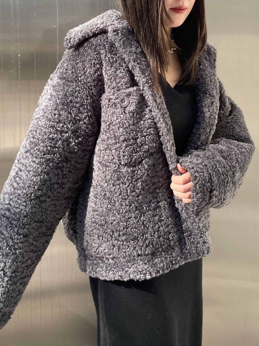 グレー系のブルゾン、ブラック系のワンピース、ブラック系のブーツを着用したレディースの冬コーディネートの4枚目の写真