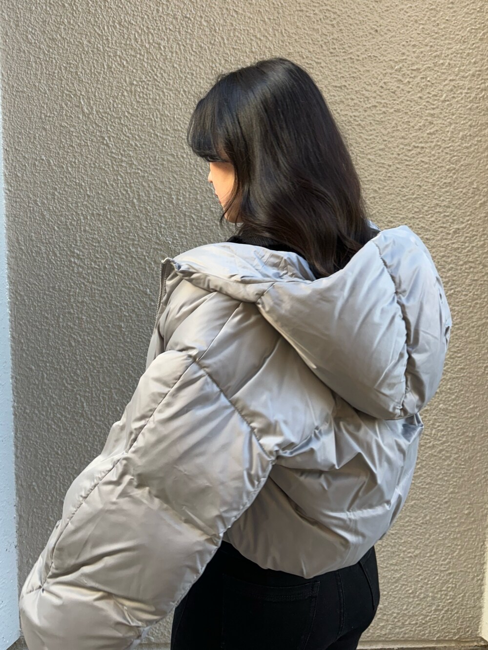 ブルー系のニット/セーター、グレー系のダウンジャケット/コート、ブラック系のデニムパンツを着用したレディースの冬コーディネートの5枚目の写真